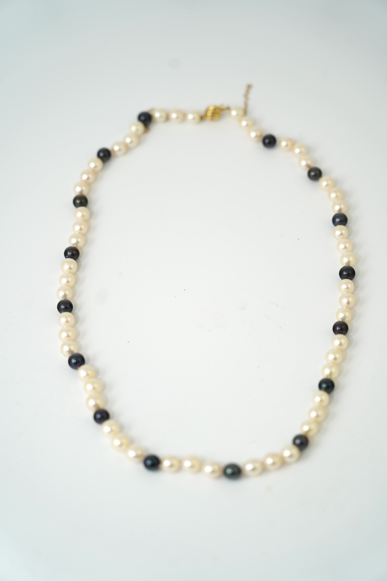 A modern single strand two colour cultured pearl necklace, with 750 yellow metal clasp, 58cm. Condition - fair